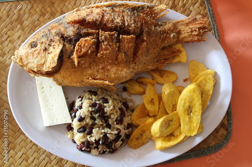 Fried central american or caribbean fish with plantain chips, rice and beans or casamiento and honduran cheese taken in Lago de Yojoa, Honduras, traditional food from Honduras 