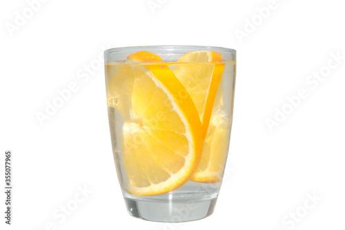 Clear liquid in clear glass with orange pieces inside isolated on white background