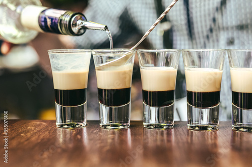 Bartender is preparing array of three layer shots at bar in Vilnius, Lithuania