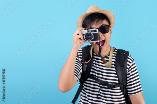 Happy Asian backpackers traveling to take pictures on a blue background in the studio.
