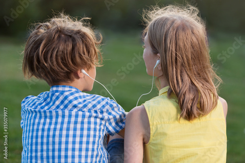 boy and girl listening to music using headphones for two, camping together, close-up © aneduard