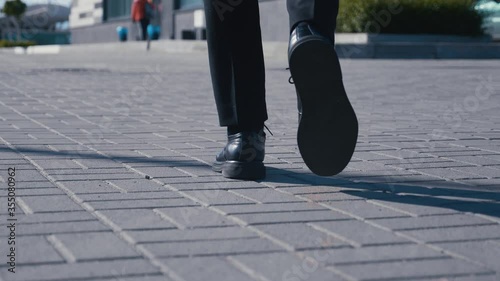 Rear back view feet of businessman commuting to work. Confident guy in leather shoes and suit being on his way to office building