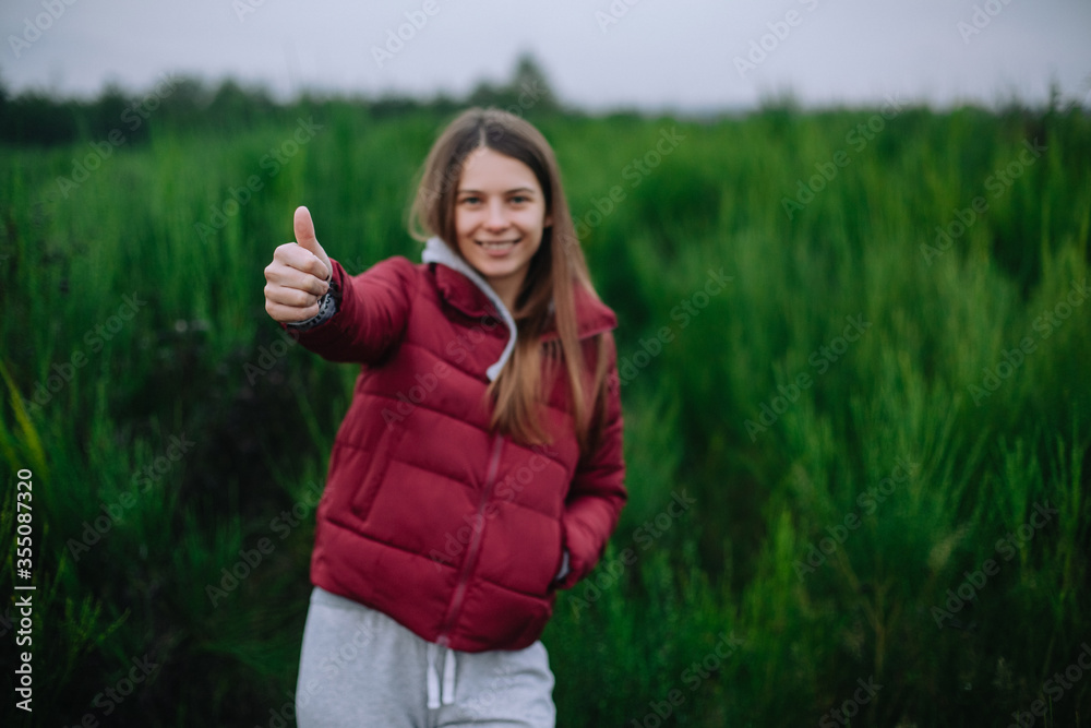Happy girl in autumn clothes on a background of nature shows class. Happy girl in autumn clothes on a background of nature shows class.
