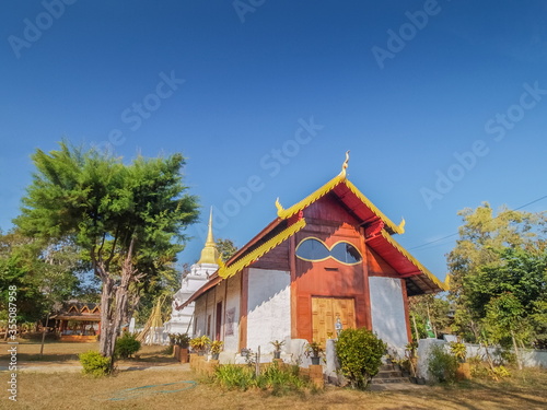 view of buddhist temple design with glasses window around with green forest and blue sky background, Wat Chan Temple, famous attraction in Kalayaniwattana District, Chiang Mai, northern of Thailand.