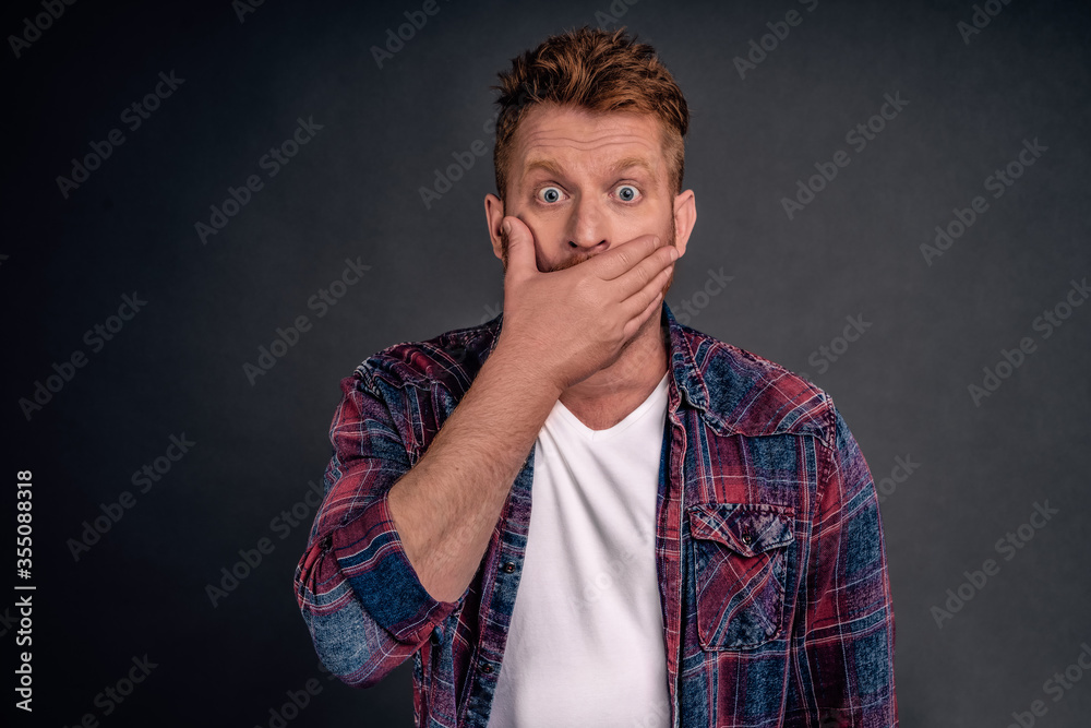 Man hearing fresh rumors shocked and amazed, covering opened mouth with palm while gasping, staring with popped eyes at camera cannot believe shocking thing happened, hearing gossip over gray wall Man hearing fresh rumors shocked and amazed, covering opened mouth with palm while gasping, staring with popped eyes at camera cannot believe shocking thing happened, hearing gossip over gray wall