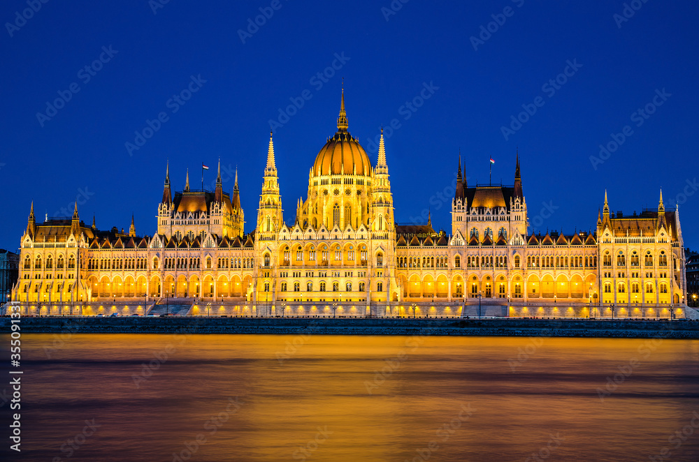 Hungarian Parliament lit at night during blue hour, view from across the Danube river, Budapest, Hungary