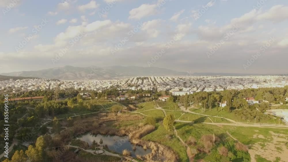 AERIAL city view with a amazing green park above trees and small lake city building at background sunny day with few clouds in sky AERIAL city view with a amazing green park above trees and small lake city building at background sunny day with few clouds in sky