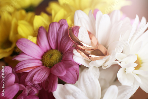 Closeup of wedding rings on color flowers