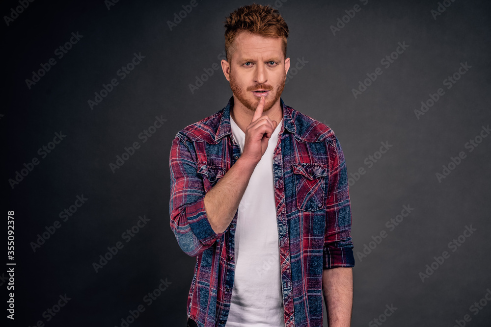 Shh, I need silence to focus on work. Portrait of handsome serious-looking and strict father with red hair and bristle, frowning, making shush gesture with index finger over mouth, asking keep quiet Shh, I need silence to focus on work. Portrait of handsome serious-looking and strict father with red hair and bristle, frowning, making shush gesture with index finger over mouth, asking keep quiet