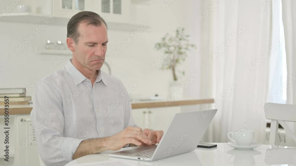 Upset Middle Aged Man with Laptop doing Thumbs Down Upset Middle Aged Man with Laptop doing Thumbs Down