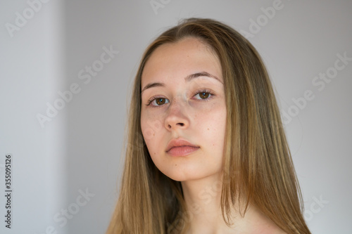 Close up portrait of a pretty and charming young woman with smooth skin posing looking at the camera on a grey background
