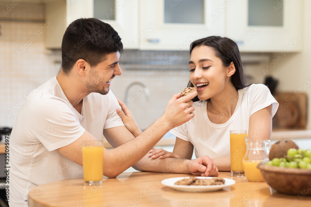 Smiling man feeding his girl, couple having breakfast together Smiling man feeding his girl, couple having breakfast together
