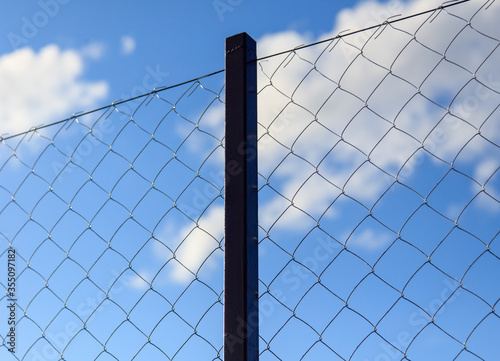 Metal mesh on the fence against the sky. © schankz