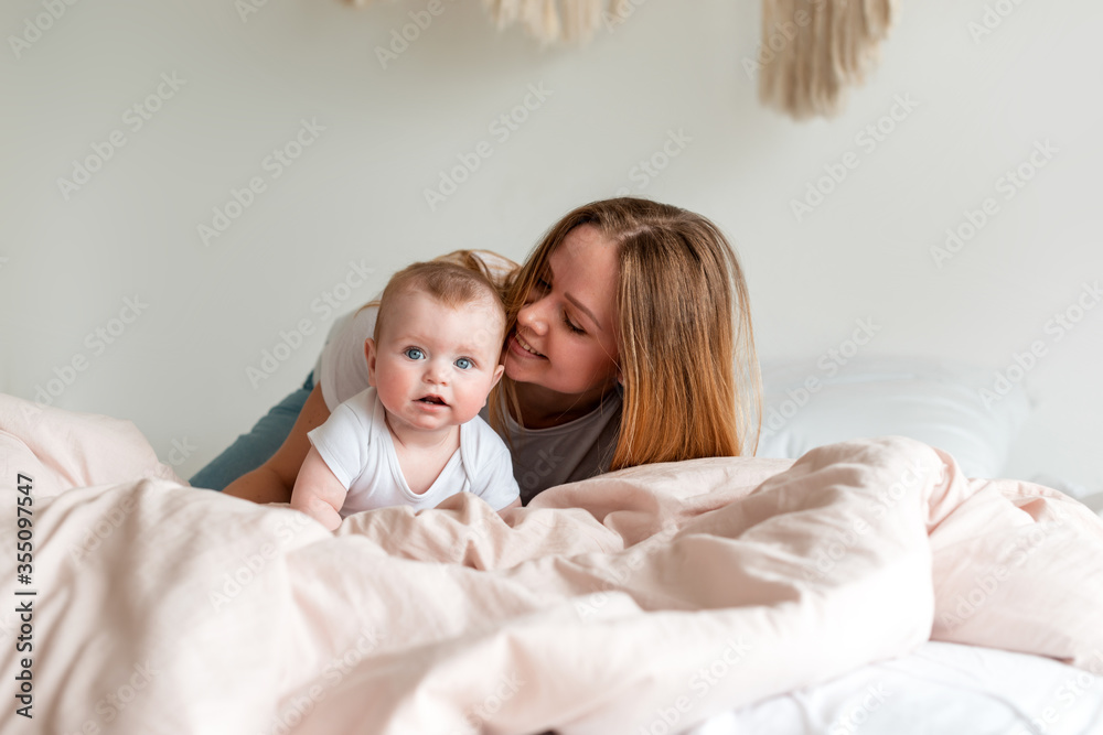 Beautiful young mother and newborn baby lying on the bed in the bedroom Beautiful young mother and newborn baby lying on the bed in the bedroom