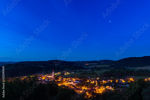 High angle view over the town Zell in Germany, Bavaria, Upper Palatinate at night with starry sky and clouds