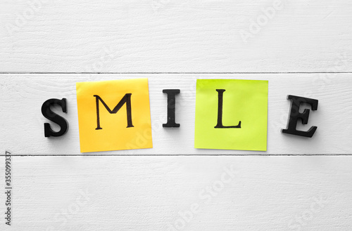 Word SMILE on white wooden background