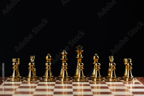 Golden chess figures standing on chessboard