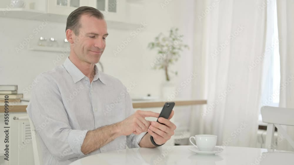 Attractive Middle Aged Man using Smartphone at Home Attractive Middle Aged Man using Smartphone at Home