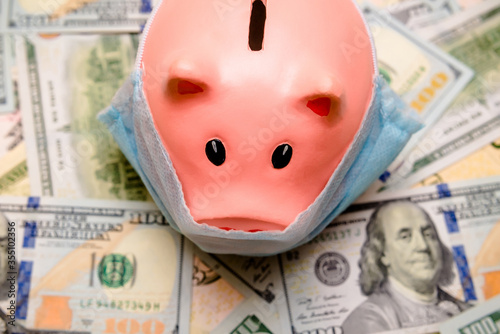 piggy bank in a mask on a background of american currency.The concept of coronavrius epidemic
