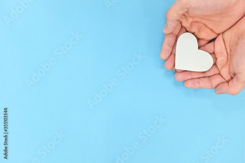 Canvas Print Cupped hands holding a white heart in blue background
