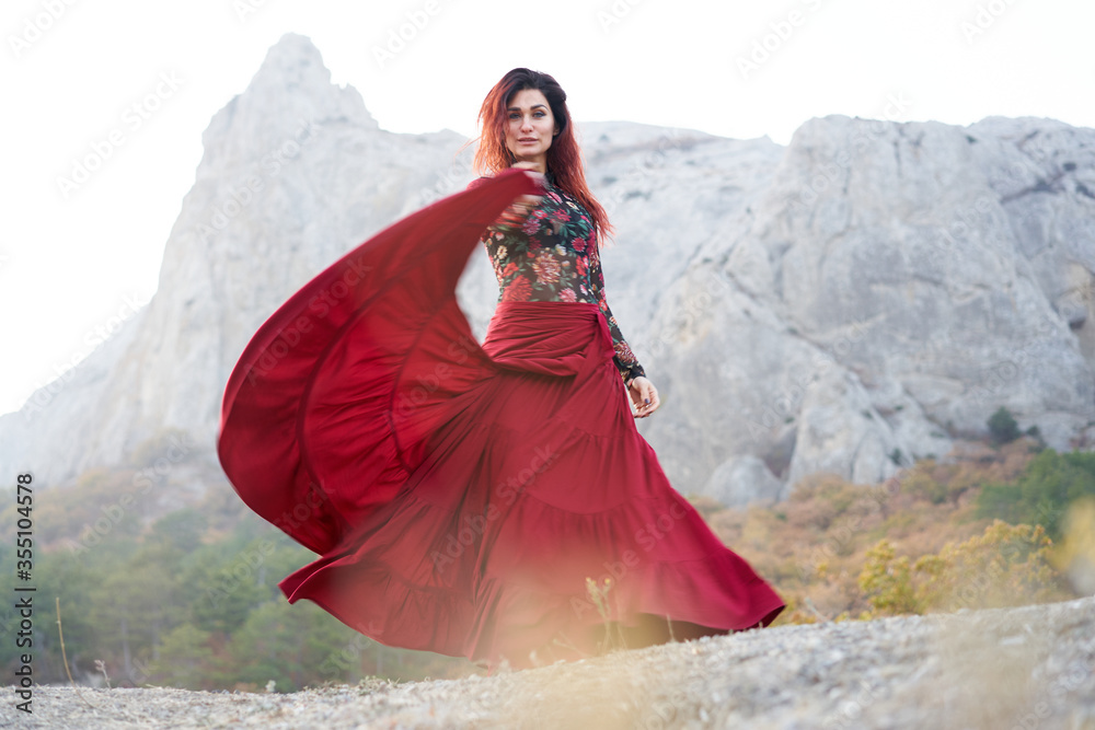 Woman in red long dress dancing on mountains view Woman in red long dress dancing on mountains view
