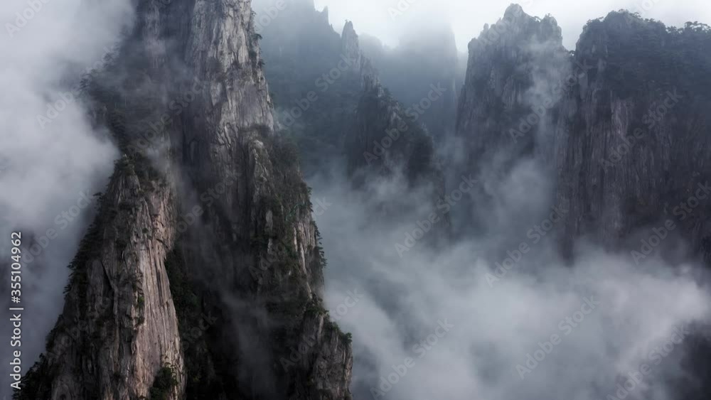 Beautiful mountain peaks appearing through low clouds, Huangshan China, rising aerial view