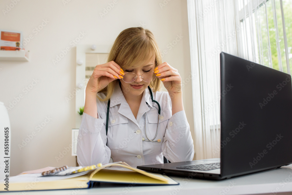 young stressed woman doctor sitting in modern office.tired doctor at the computer. online consultation. young stressed woman doctor sitting in modern office.tired doctor at the computer. online consultation.
