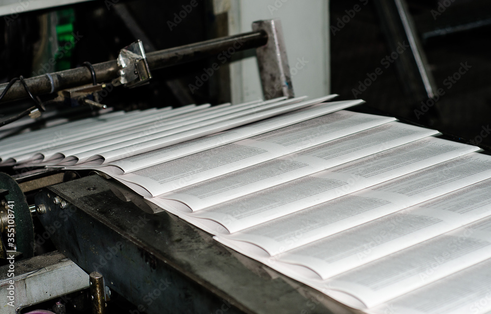 Printing paper Newspapers in the printing house. Printed publications on the industrial conveyor. Publishing house. Latest news release. Fresh press. Printing paper Newspapers in the printing house. Printed publications on the industrial conveyor. Publishing house. Latest news release. Fresh press.