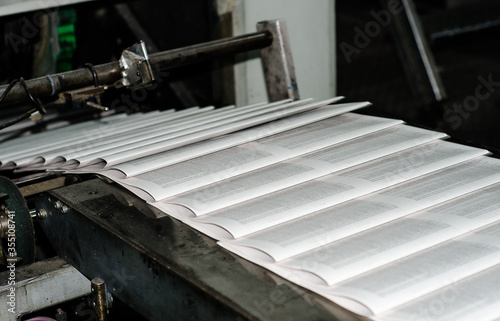 Printing paper Newspapers in the printing house. Printed publications on the industrial conveyor. Publishing house. Latest news release. Fresh press.
