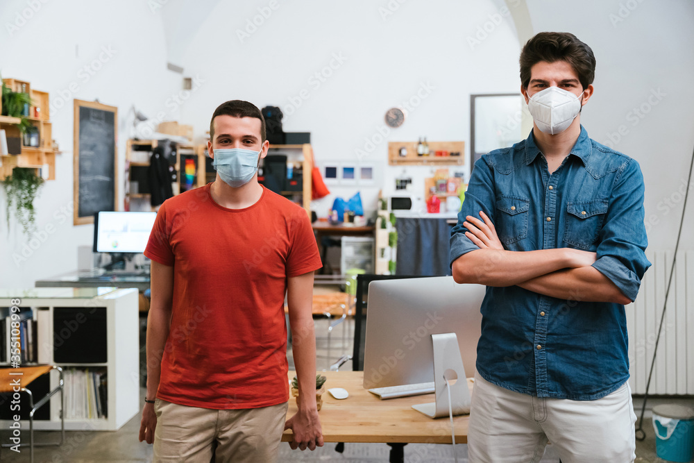 Obraz premium Portrait of millennials men with surgical mask at working in office at distance for protection and prevention from Coronavirus, Covid-19
