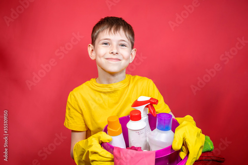A boy in yellow gloves with cleaning products 