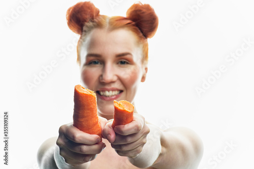 a close-up portrait of a red-haired girl with clear skin and a carrot in her hands. Isolated on a white background.