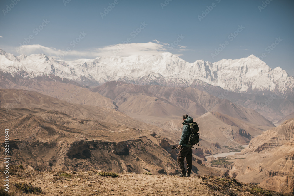 Upper mustang - Kingdom of Lo. Trekking in ancient Tibet. Sandstone massif in Nepal. high quality photo. Anapurna area. wild place.close territory. man backpacker in the mountains enjoys the view