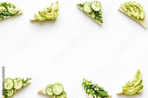 green toasts with avocado on white background from above copy space