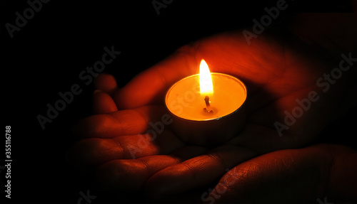 Hand holding a candle on black background,Burning candle flame