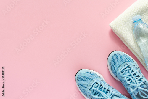 Blue sneakers and a towel with water on a pink background, playing sports or fitness, top view, healthy sport lifestyle concept