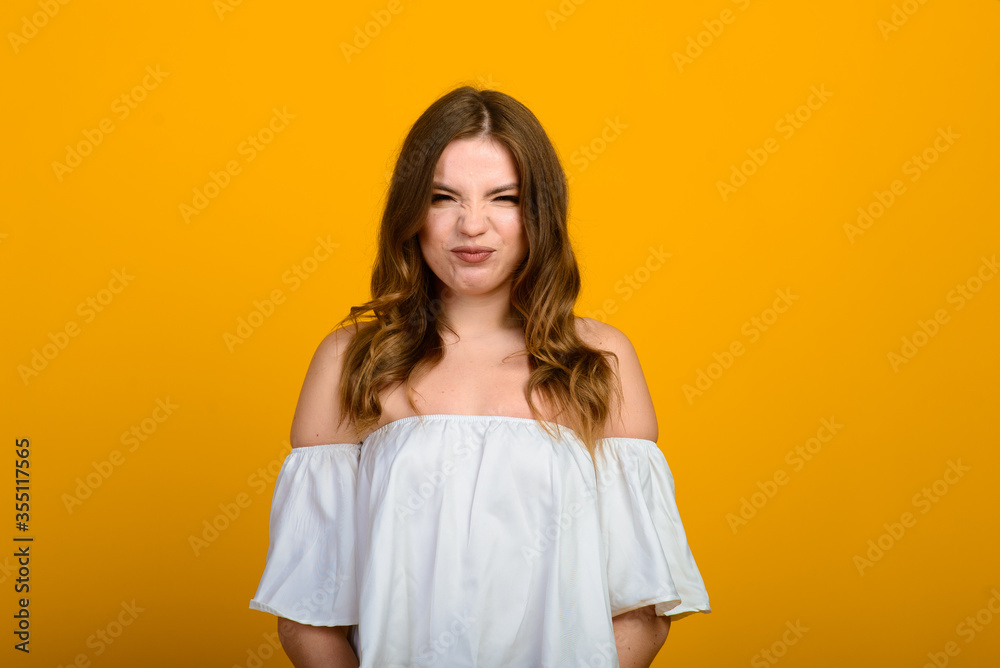 Dark-haired young woman with a smile and big suprised eyes posing on yellow background. Dark-haired young woman with a smile and big suprised eyes posing on yellow background.