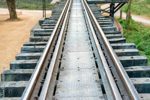 Rail track with wooden sleepers and rusty rails at old railway bridge