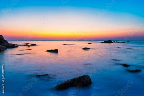 Sunset sea with rocks and evening sunset sun on dramatic sky