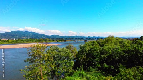 自然の中にある広大な河川に架る青い橋を空撮