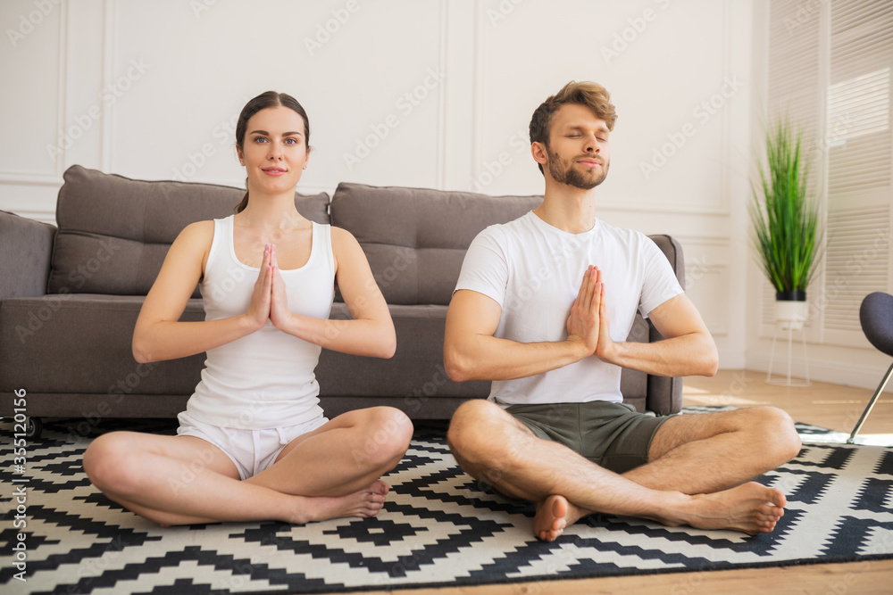 Young couple in white tshirts meditating together