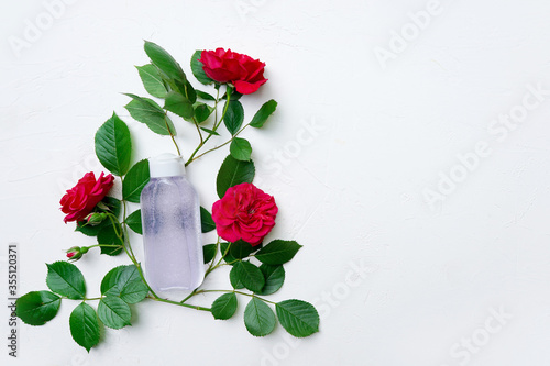 Natural organic cosmetics concept. Skin care (therapy), beauty products: container with micelar water for face with rose flowers . Close up, mock up photo