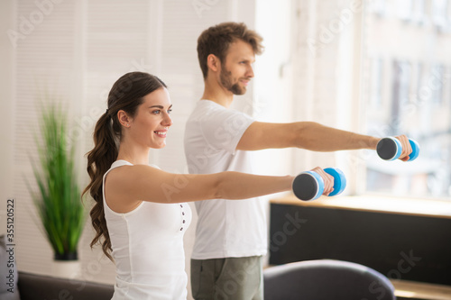 Dark-haired woman and her husband having workout together and feeling great