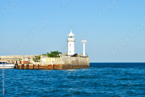 White old lighthouse on pier near blue sea