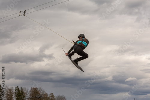 Teen boy make an extreme jump on wakeboarding, around there are a lot of splashes. Upside down on a wakeboard.