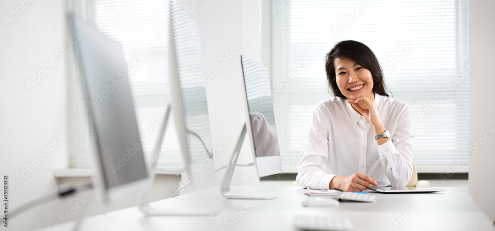 Asian business woman smiling at camera in an office Asian business woman smiling at camera in an office