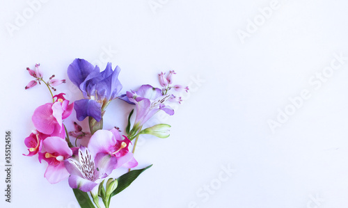 Delicate floral arrangement - lilac Alstroemeria and irises and pink orchids on a white background. Pastel shade. Background for greetings, invitations, and postcards. photo