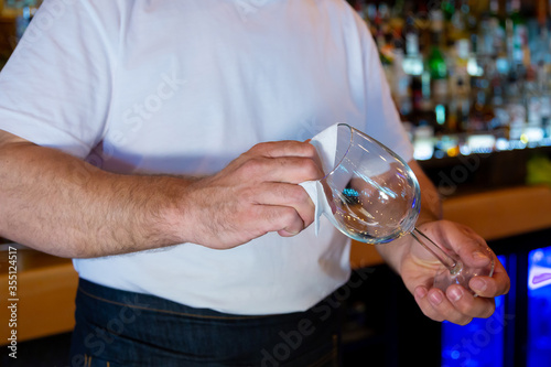 Bartender at the Bar Cleaning a Glass.