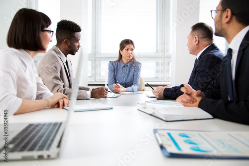International group of business people working and communicating sitting near office desk.
