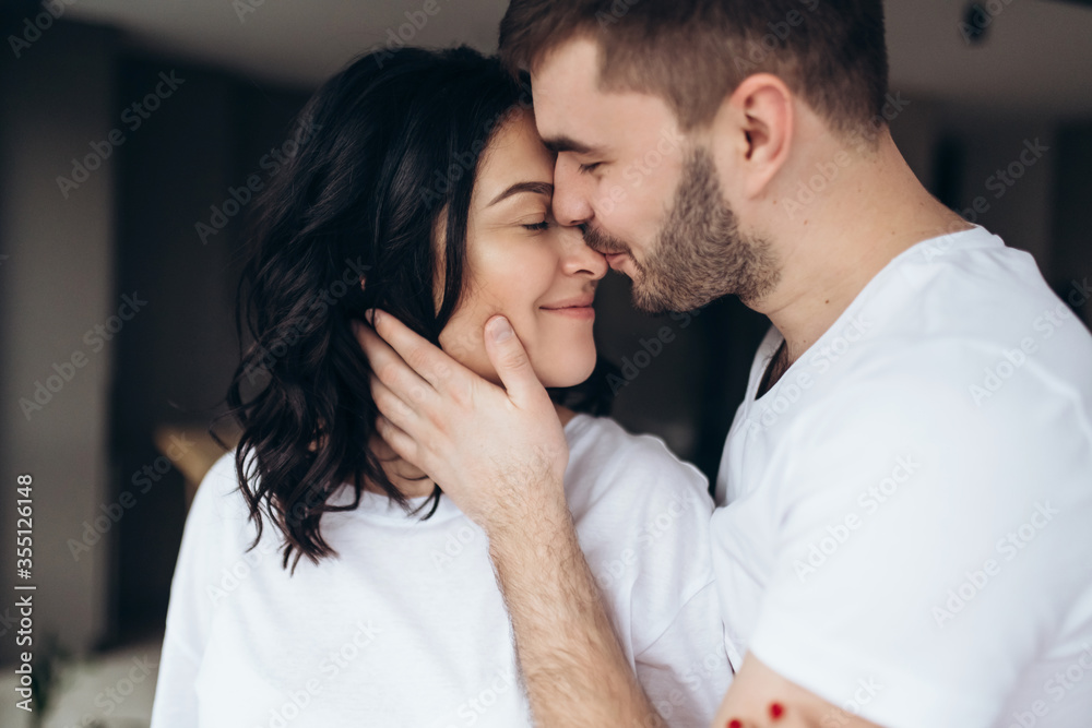 Stunning sensual intdoor portrait of young stylish fashion couple in love. Woman and man embrace and want to kiss each other. They are smiling and looking to each other Stunning sensual intdoor portrait of young stylish fashion couple in love. Woman and man embrace and want to kiss each other. They are smiling and looking to each other